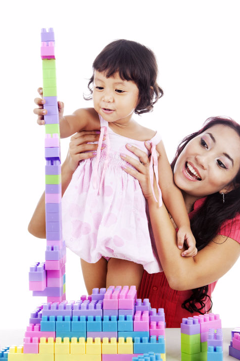 Toddler girl with mom buildign a lego tower